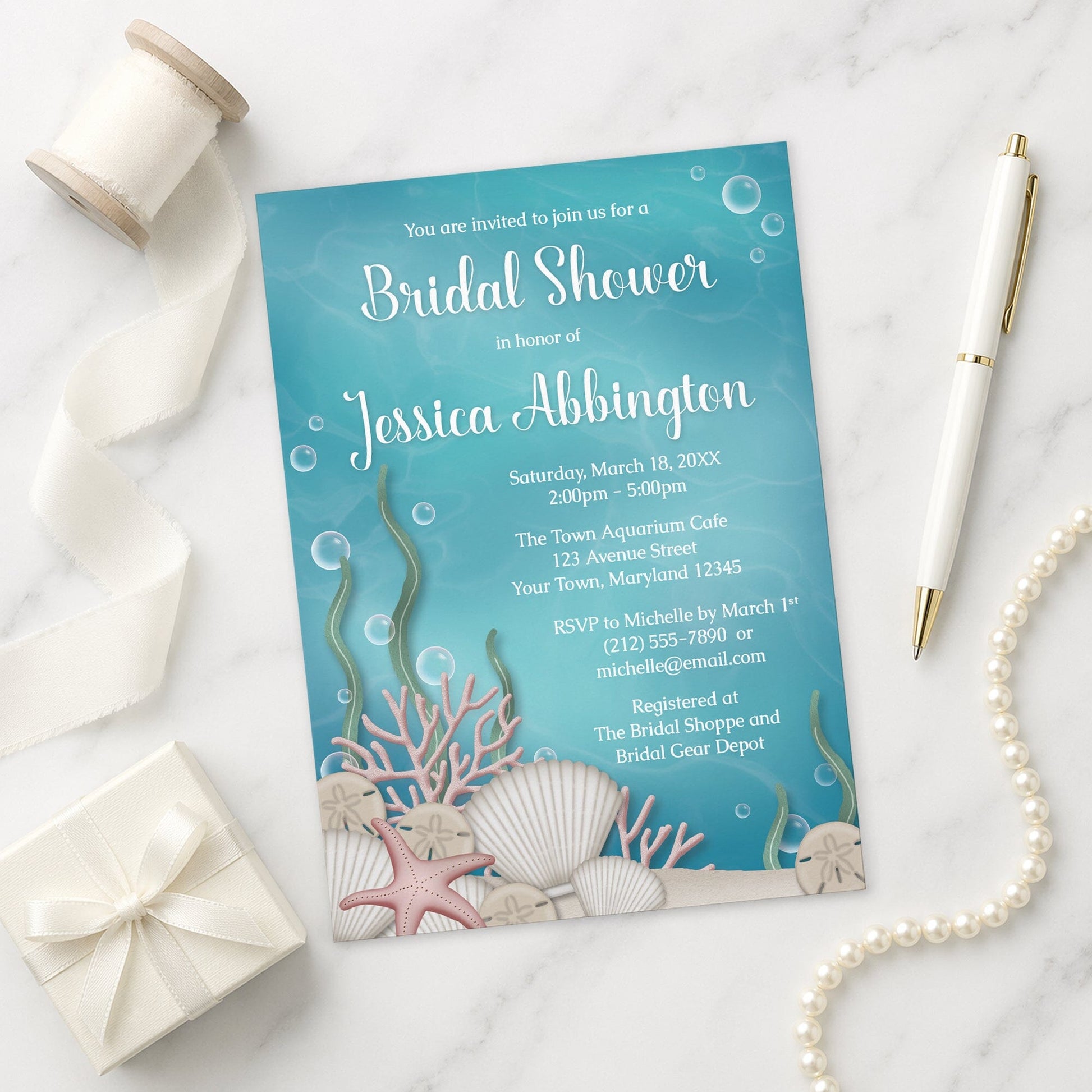 Underwater-themed Whimsical Under the Sea Bridal Shower Invitation on a marble surface with a gift box, pearls, and pen.