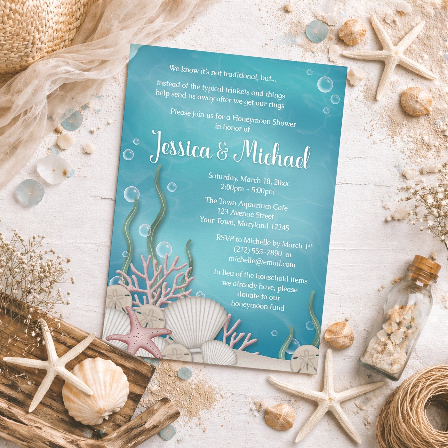 Whimsical Under the Sea Honeymoon Shower Invitation shown on a light surface with seashells, beach sand, drift wood, and coastal decor.