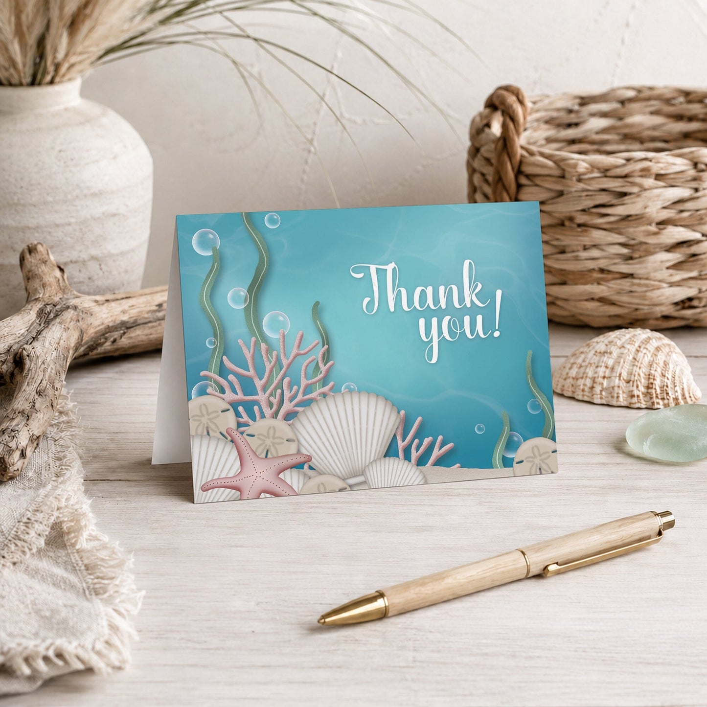 Whimsical Under the Sea Thank You Card shown on a beach house tabletop with coastal decor and a pen.