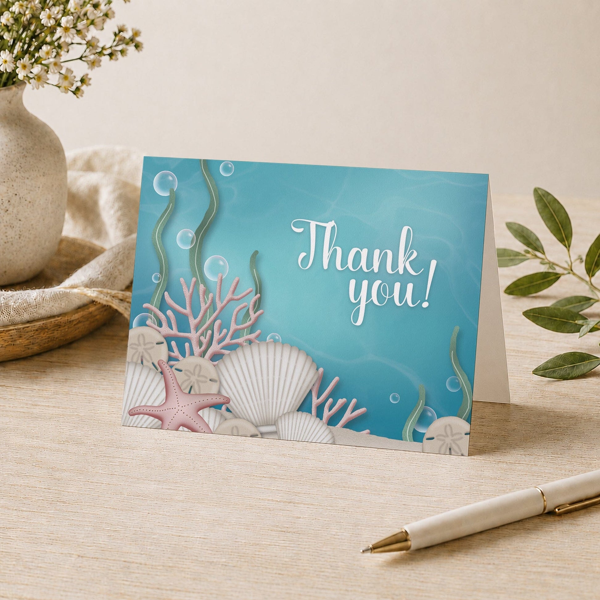 Whimsical Under the Sea Thank You Card shown on a tabletop with a vase, plants, and a pen.
