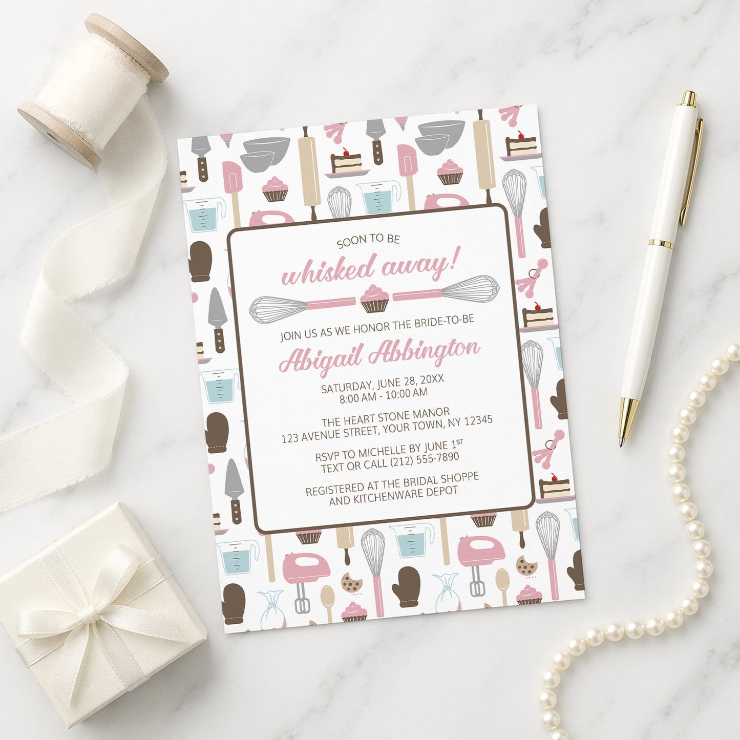 Whisked Away Pink Baking Bridal Shower Invitation with kitchen-themed pattern on a marble surface with decorative items.