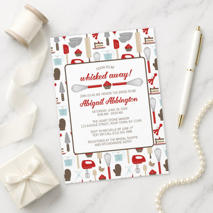Whisked Away Red Baking Bridal Shower Invitation with kitchen-themed design on a marble surface with decorative items.