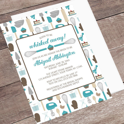 Whisked Away Turquoise Baking Bridal Shower Invitation with a kitchen tools and sweets theme, shown at an angle on a wooden surface with a white envelope.