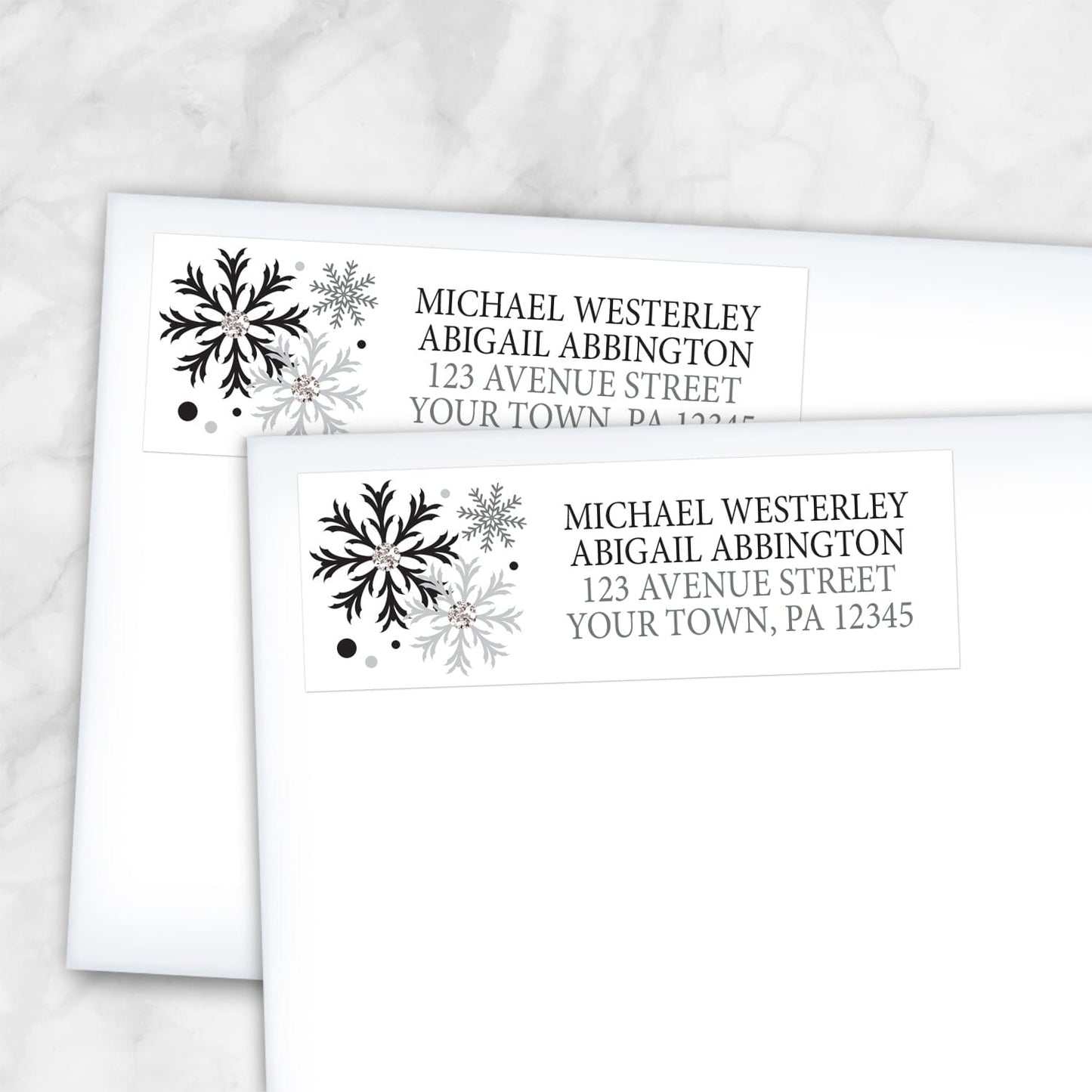2 Winter Black Silver Snowflake Address Labels shown on white envelopes on a marble surface