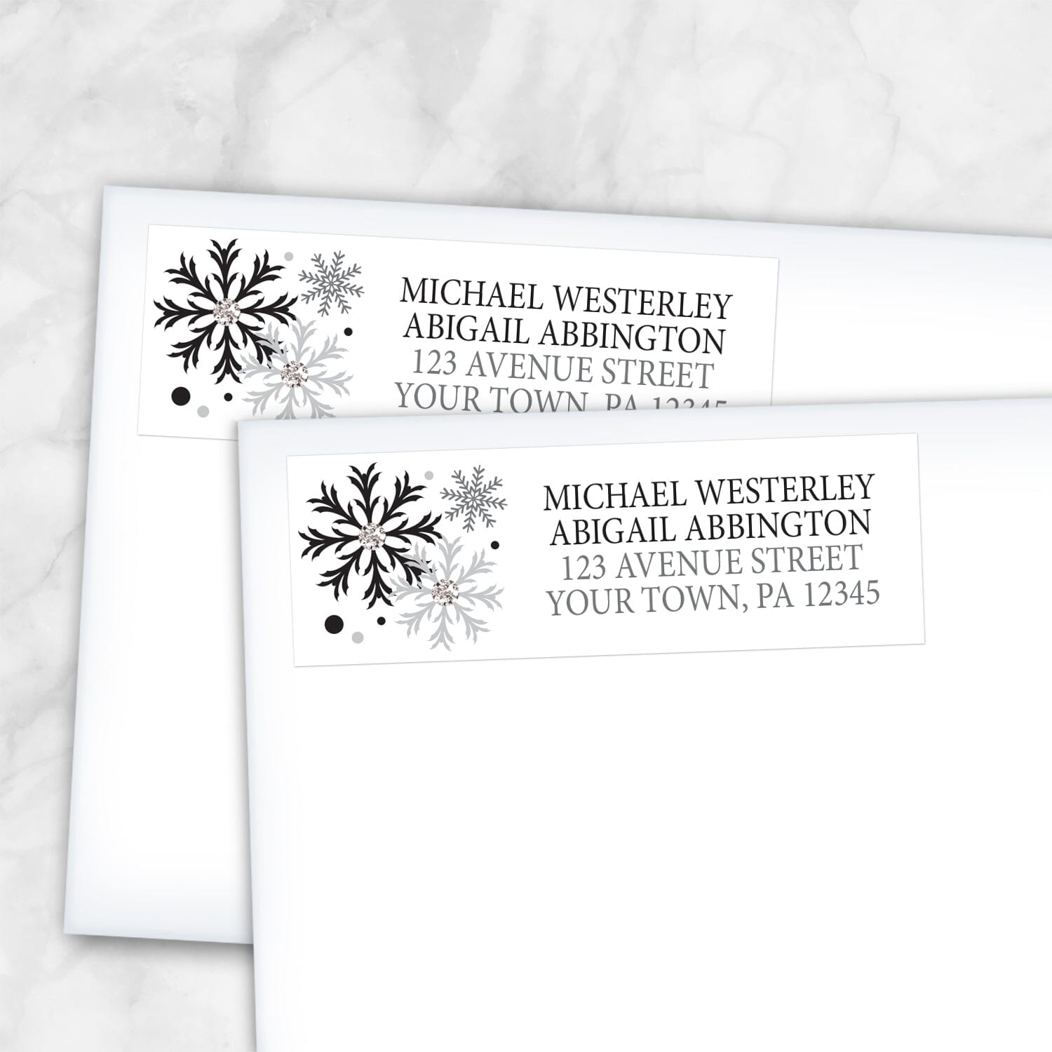 2 Winter Black Silver Snowflake Address Labels shown on white envelopes on a marble surface