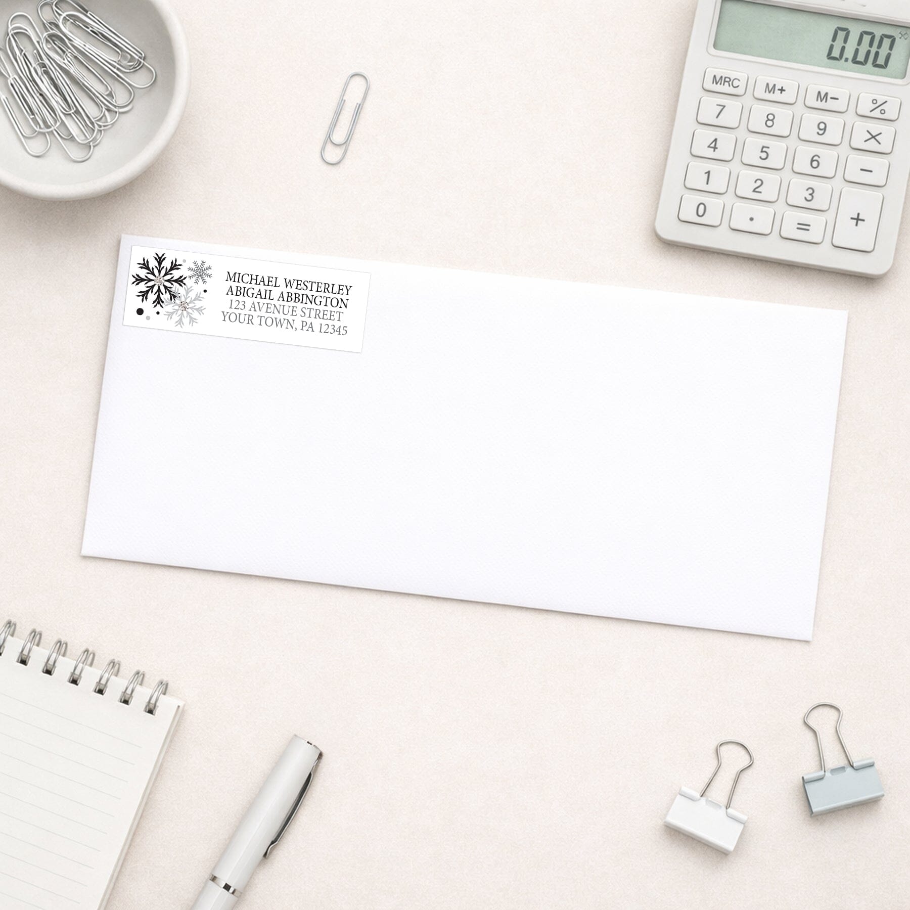 Winter Black Silver Snowflake Address Label shown on a white envelope with everyday office supplies