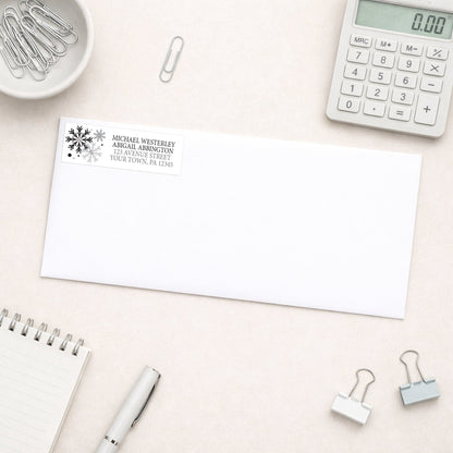 Winter Black Silver Snowflake Address Label shown on a white envelope with everyday office supplies