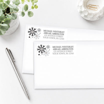 Winter Black Silver Snowflake Address Labels, shown on white envelopes, on a white surface with a pen and plant.