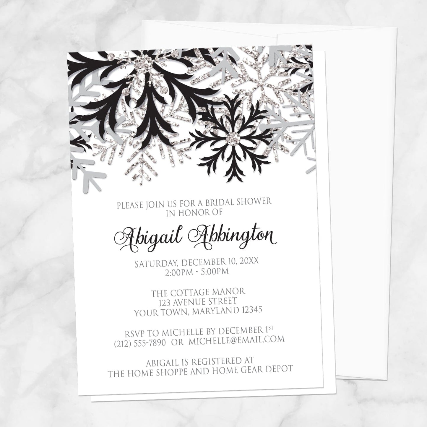 Winter Black Silver Snowflake Bridal Shower Invitation shown on a marble surface with a white envelope.