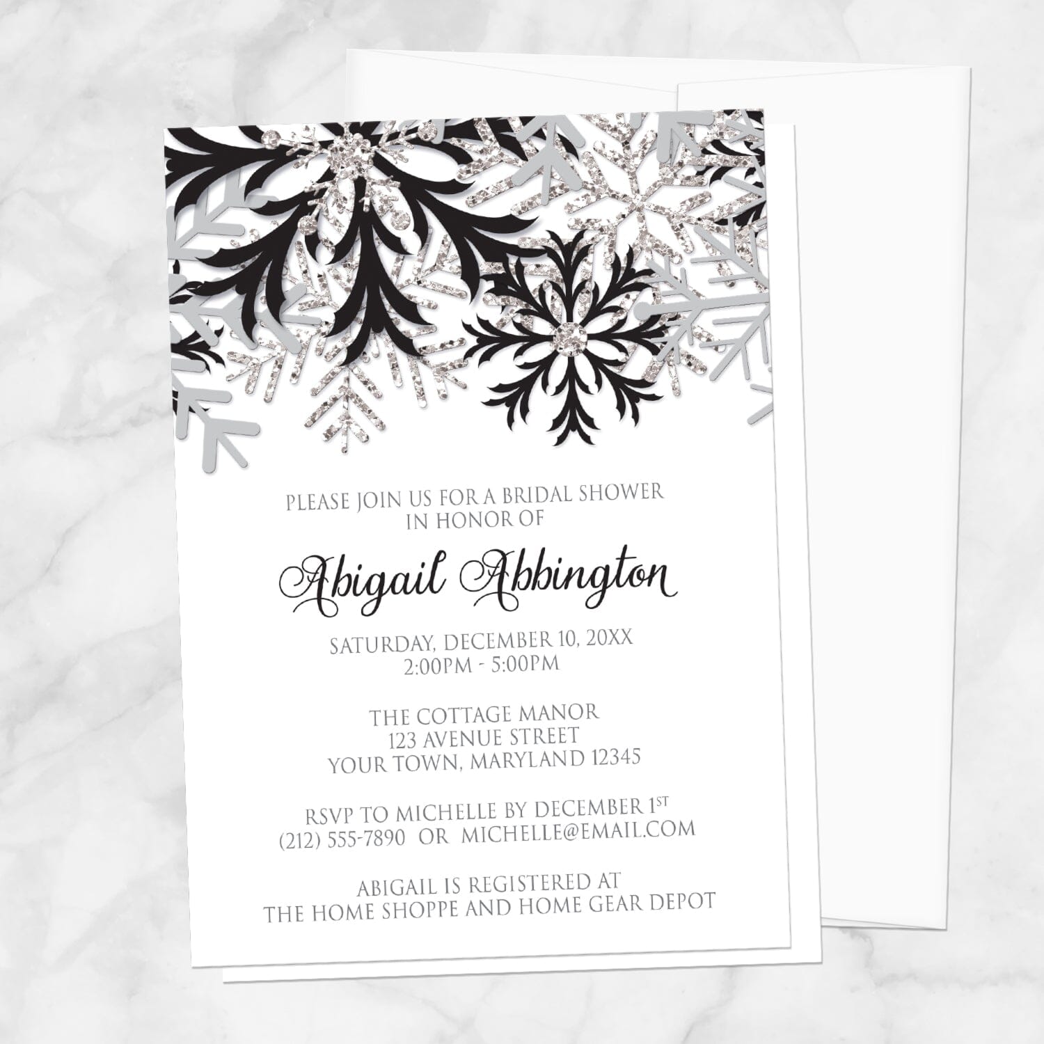 Winter Black Silver Snowflake Bridal Shower Invitation shown on a marble surface with a white envelope.