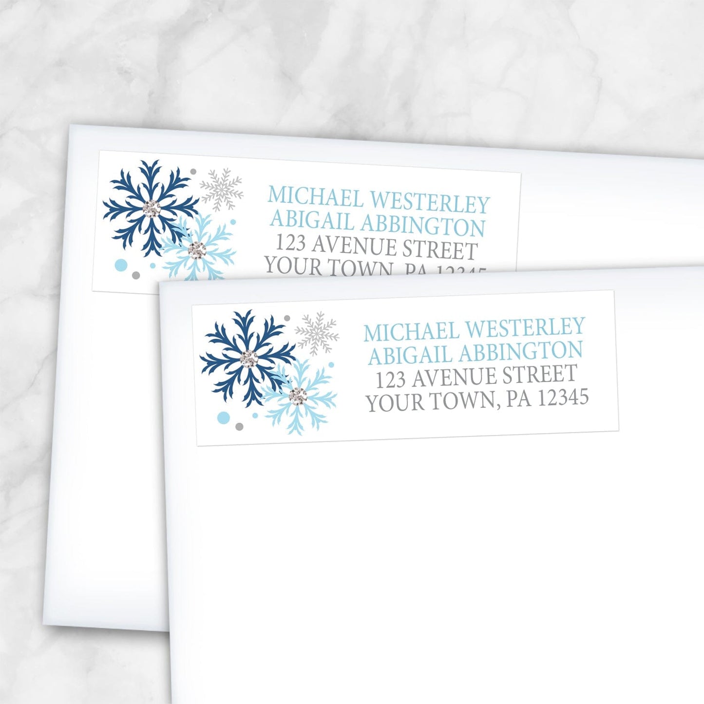 2 Winter Blue Silver Snowflake Address Labels shown on white envelopes on a marble surface