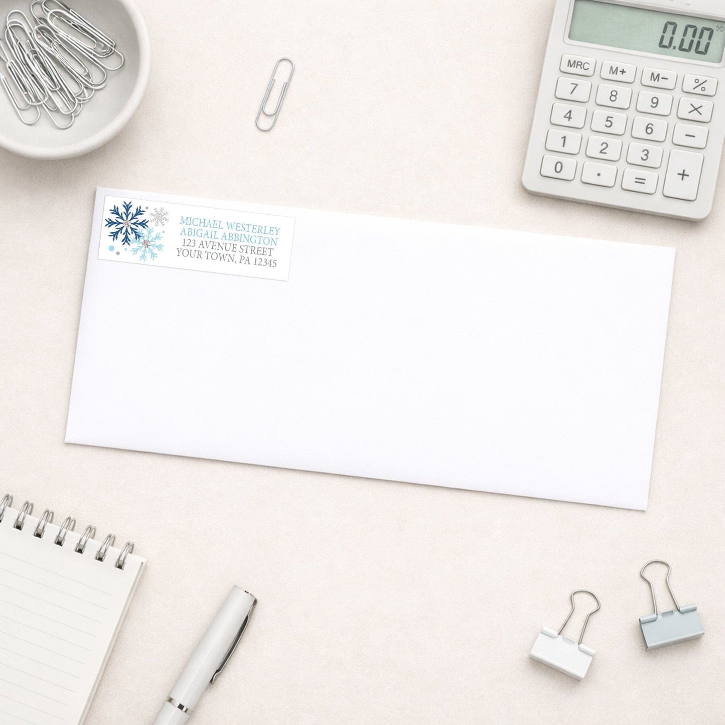 Winter Blue Silver Snowflake Address Label shown on a white envelope with everyday office supplies