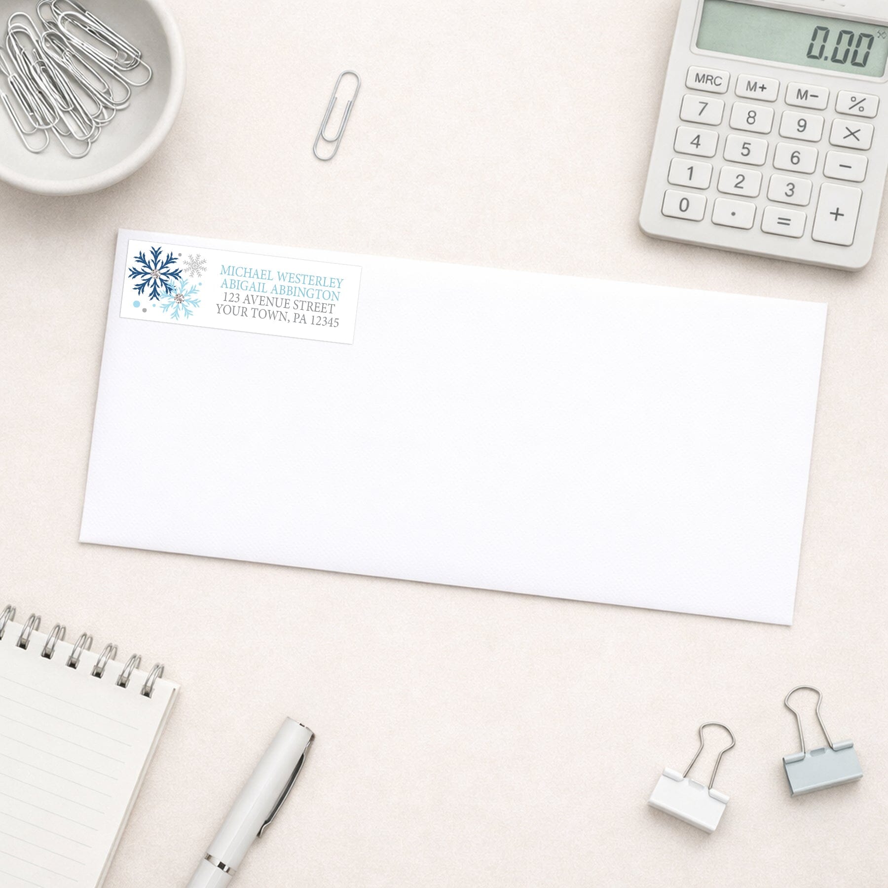 Winter Blue Silver Snowflake Address Label shown on a white envelope with everyday office supplies