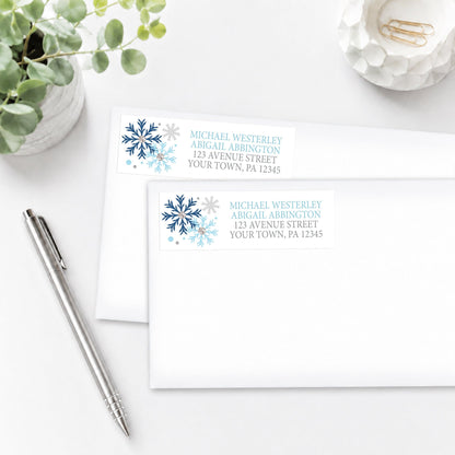 Winter Blue Silver Snowflake Address Labels shown on envelopes on a white surface with a plant and pen.