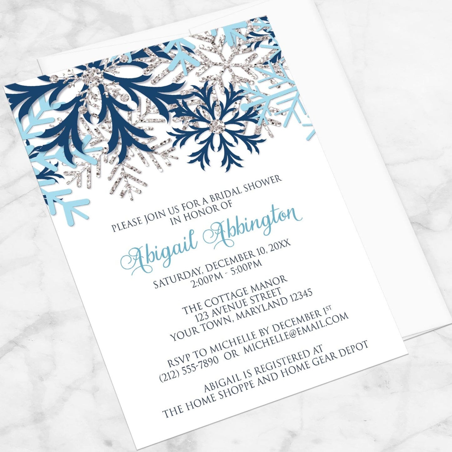 Winter Blue Silver Snowflake Bridal Shower Invitation shown at an angle on a marble surface with a white envelope.