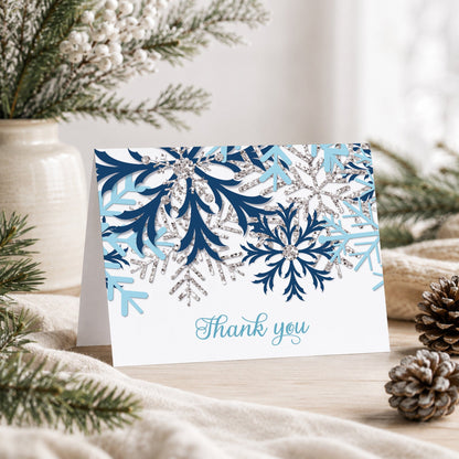 Winter Blue Silver Snowflake Thank You Card shown on a tabletop with a vase, rustic greenery, and pine cones.