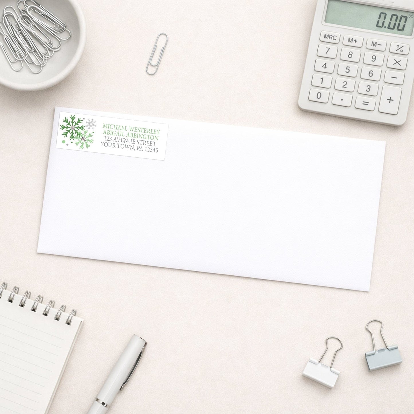 Winter Green Silver Snowflake Address Label shown on a white envelope with office supplies