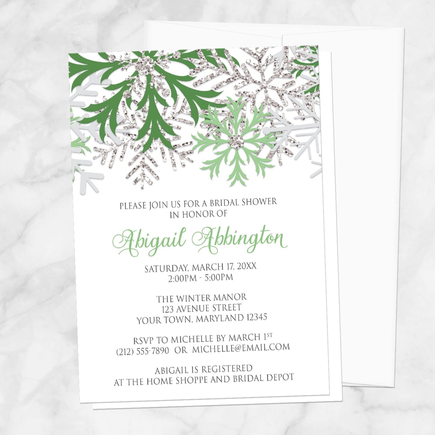Winter Green Silver Snowflake Bridal Shower Invitation shown on a marble surface with a white envelope.