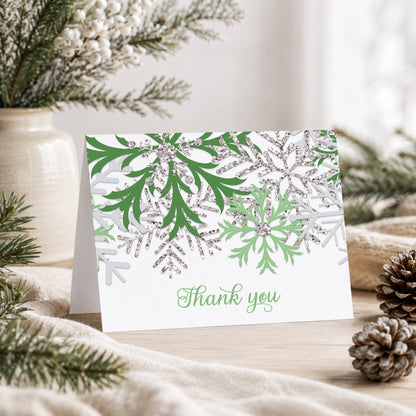 Winter Green Silver Snowflake Thank You Card shown on a tabletop with a vase, winter greenery, and pine cones.