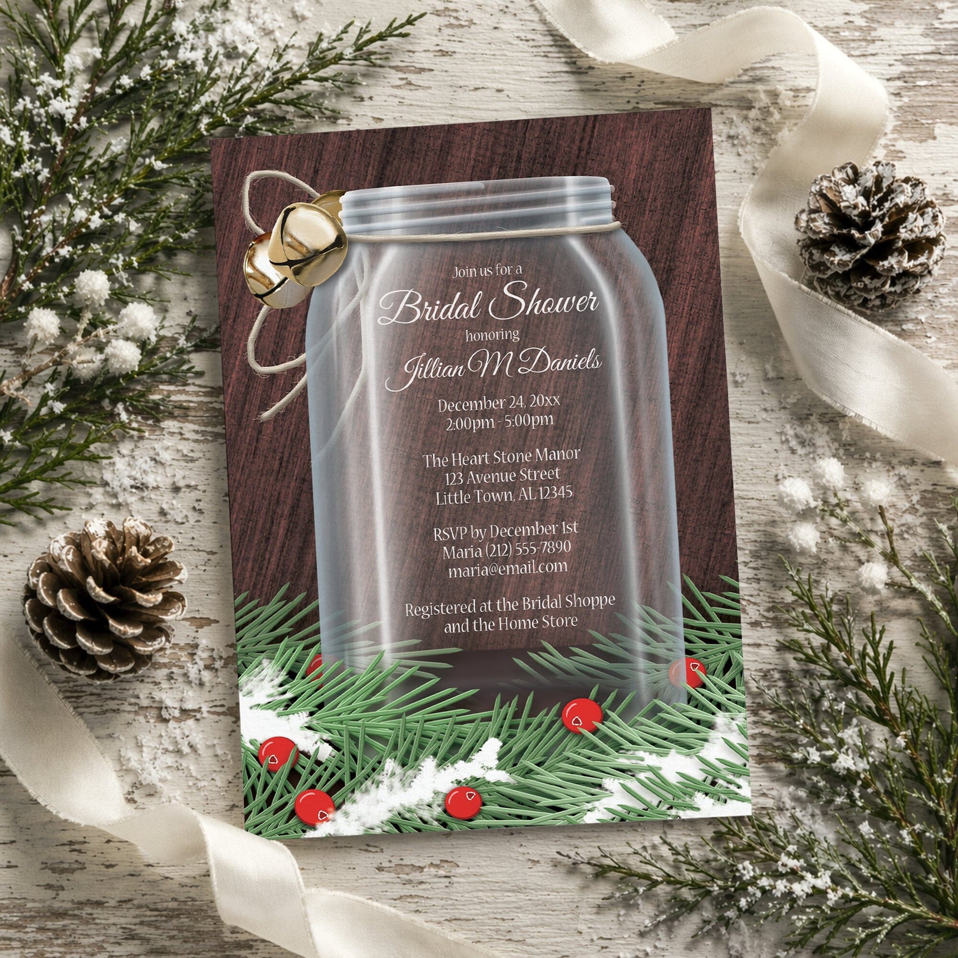 Winter Mason Jar Pine Boughs Bridal Shower Invitation shown on a rustic surface with winter greenery, pine cones, and ribbons.