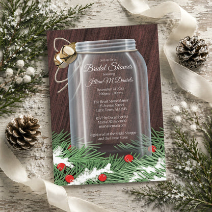 Winter Mason Jar Pine Boughs Bridal Shower Invitation shown on a rustic surface with winter greenery, pine cones, and ribbons.