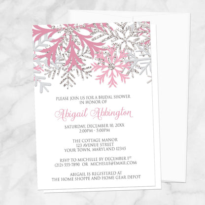 Winter bridal shower invitation with pink and silver snowflake design shown on a marble surface with a white envelope.