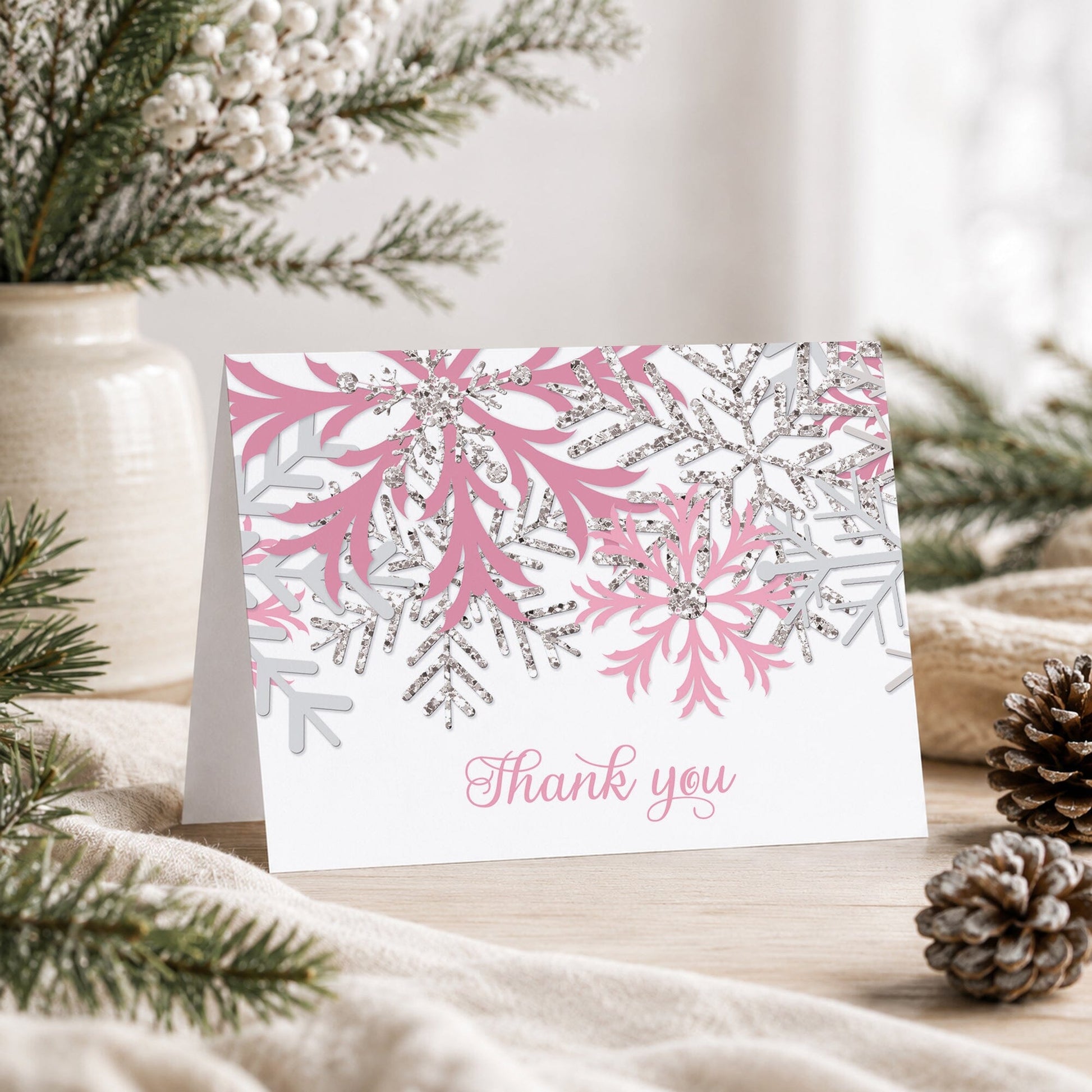 Winter Pink Silver Snowflake Thank You Card shown on a tabletop with a vase, winter greenery, and pine cones.