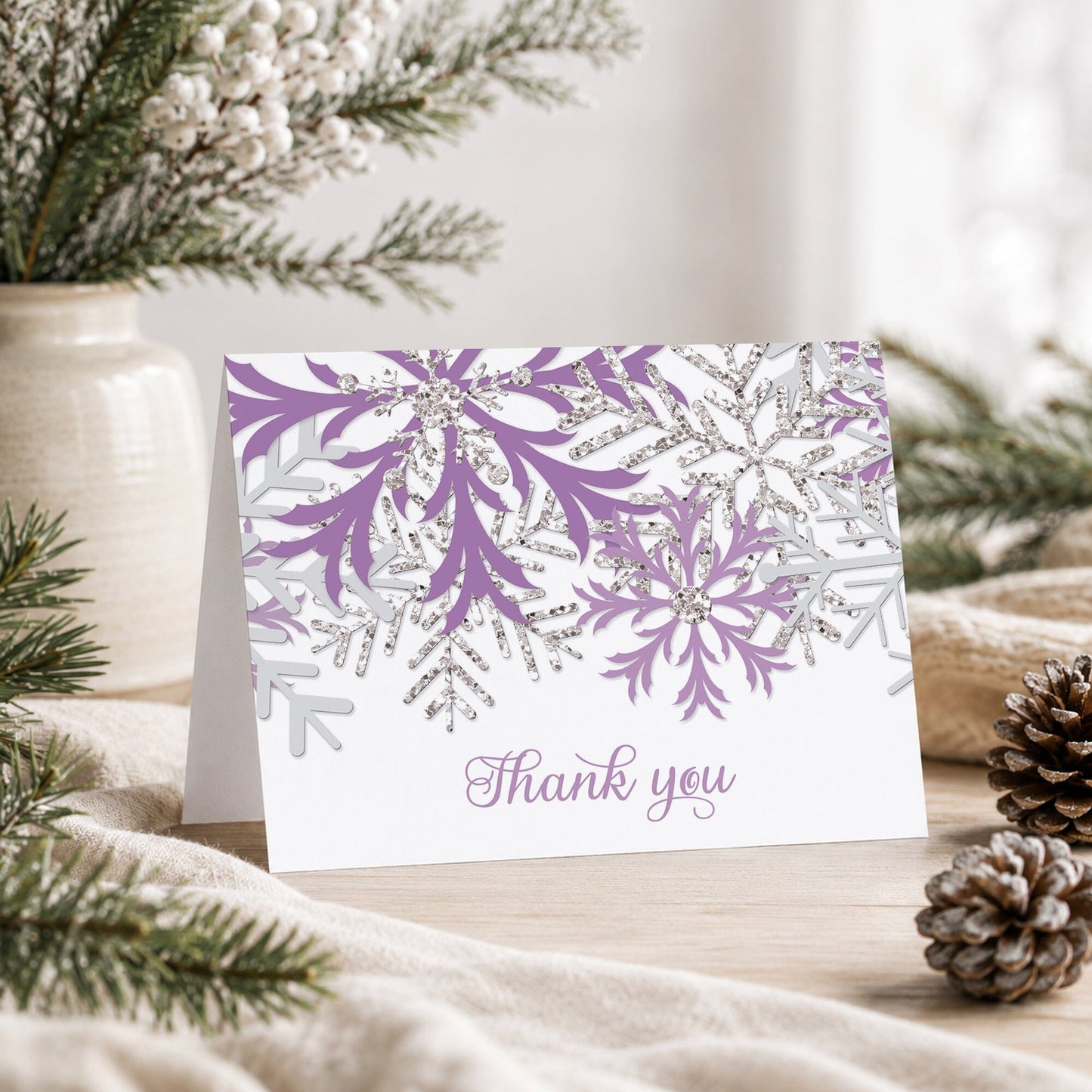 Winter Purple Silver Snowflake Thank You Card shown on a tabletop with a vase, winter greenery, and pine cones.