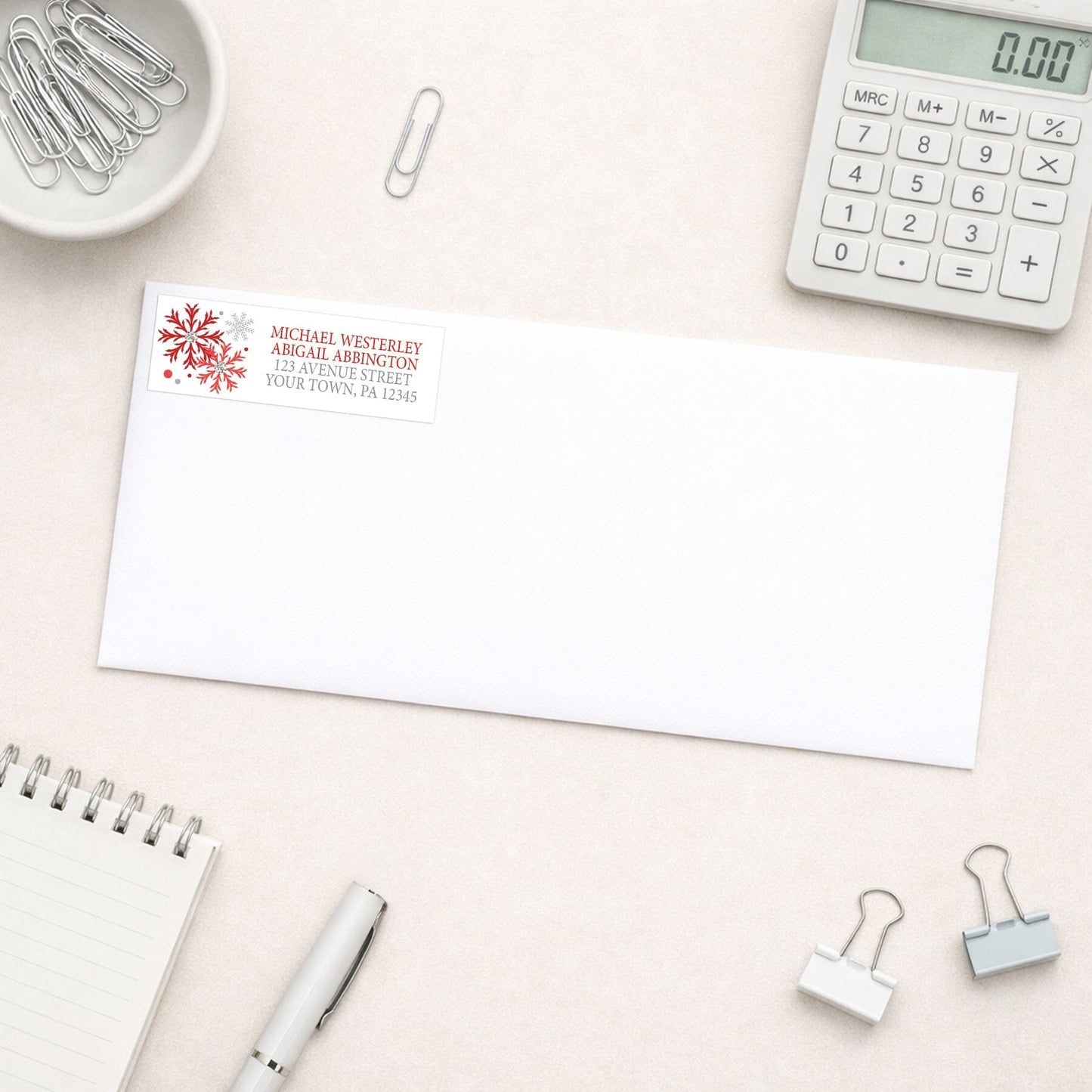 Winter Red Silver Snowflake Address Label shown on a white envelope with everyday office supplies