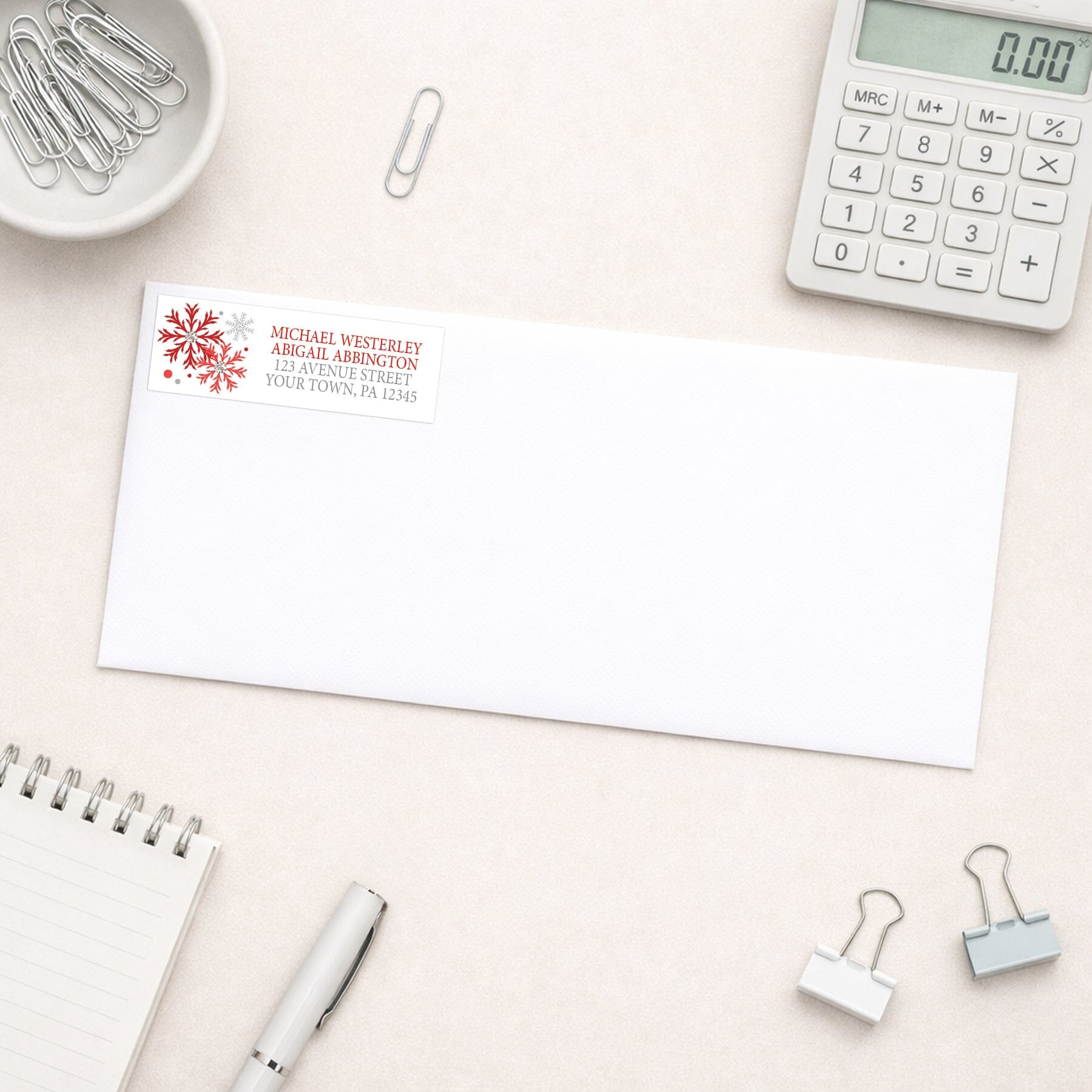 Winter Red Silver Snowflake Address Label shown on a white envelope with everyday office supplies