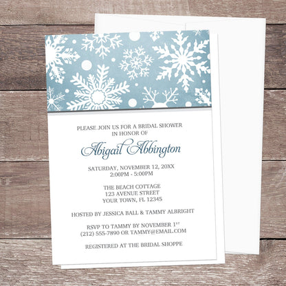 Winter Snowflake Blue Gray Bridal Shower Invitation shown on a wooden surface with a white envelope.