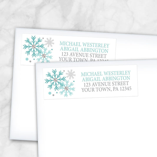 2 Winter Teal Silver Snowflake Address Labels shown on white envelopes on a marble surface
