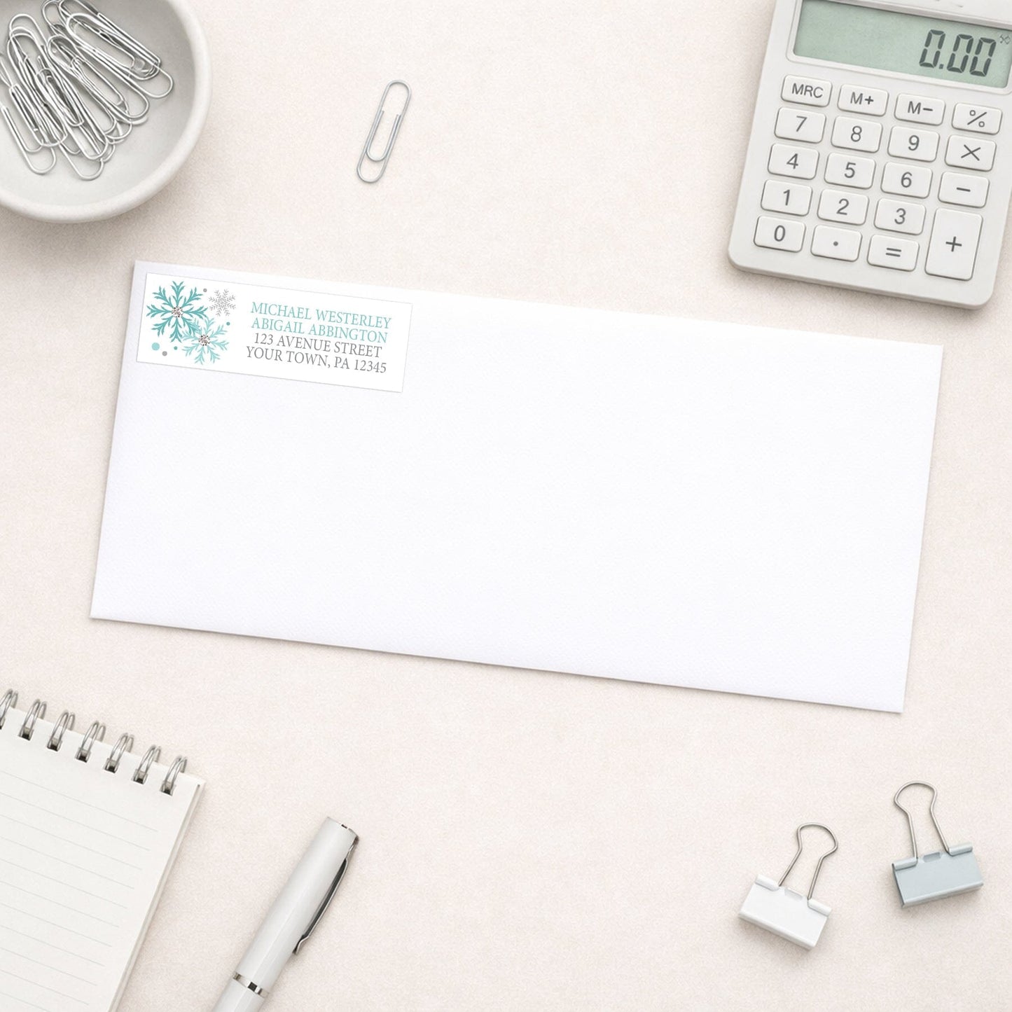 Winter Teal Silver Snowflake Address Label shown on a white envelope with everyday office supplies