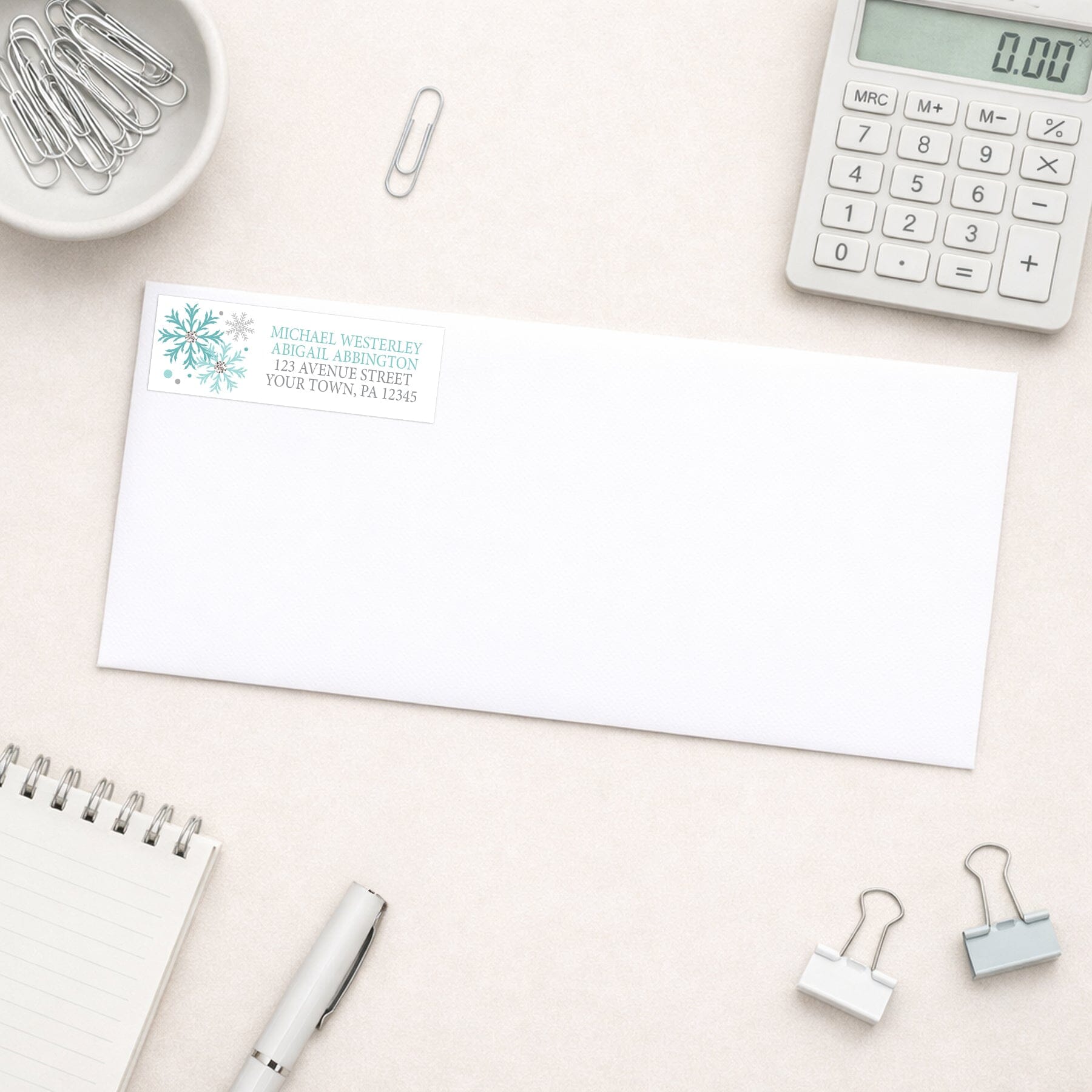 Winter Teal Silver Snowflake Address Label shown on a white envelope with everyday office supplies