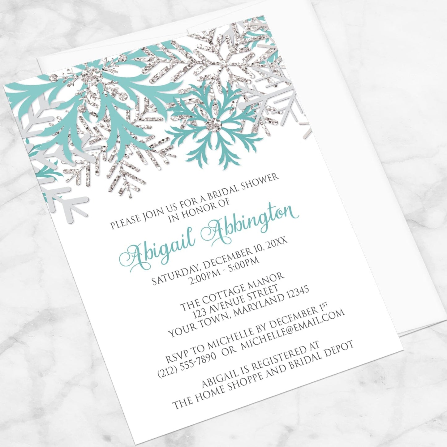Winter Teal Silver Snowflake Bridal Shower Invitation shown at an angle with a white envelope on a marble surface.