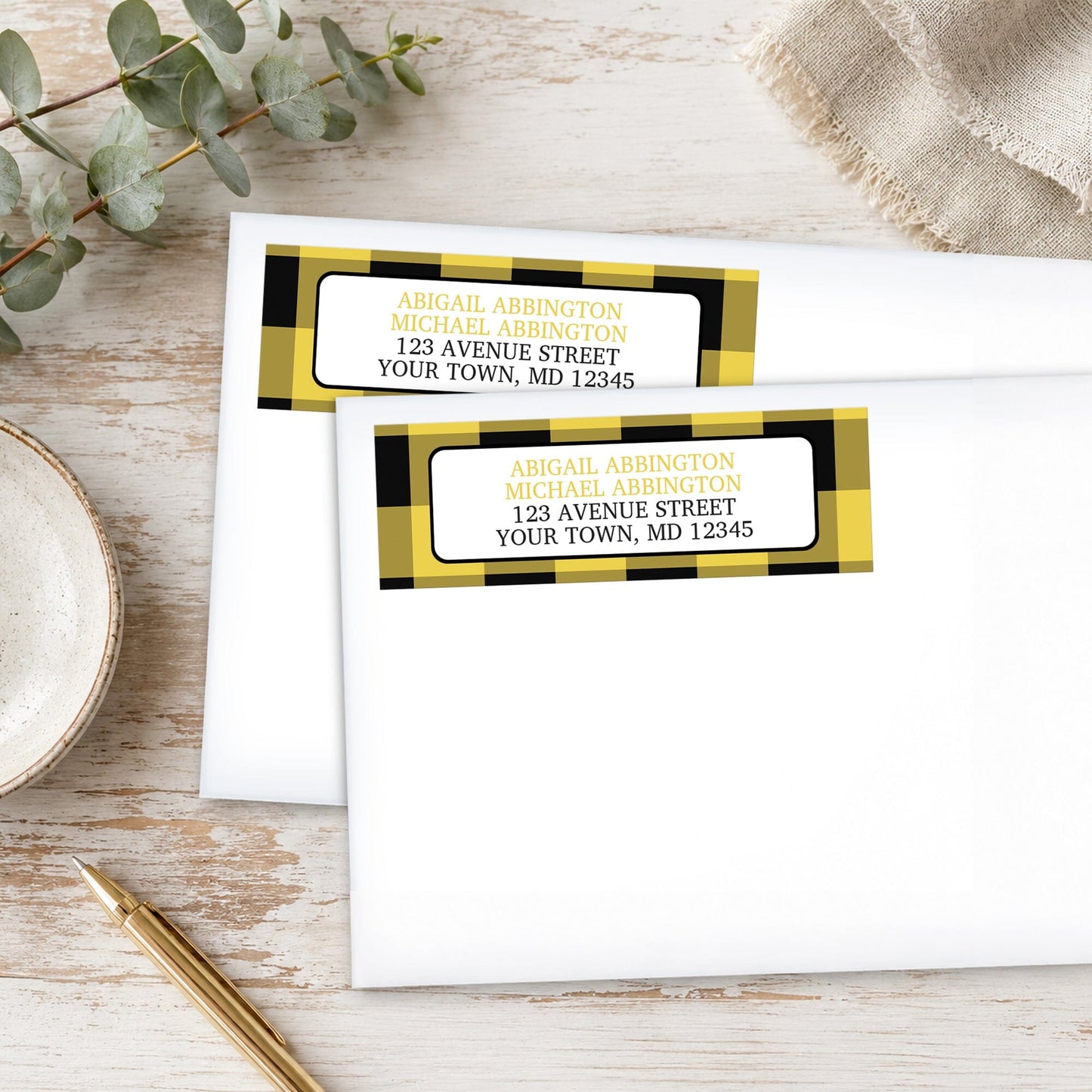Yellow and Black Buffalo Plaid Address Labels on white envelopes, shown on a wooden surface with plants and a pen.