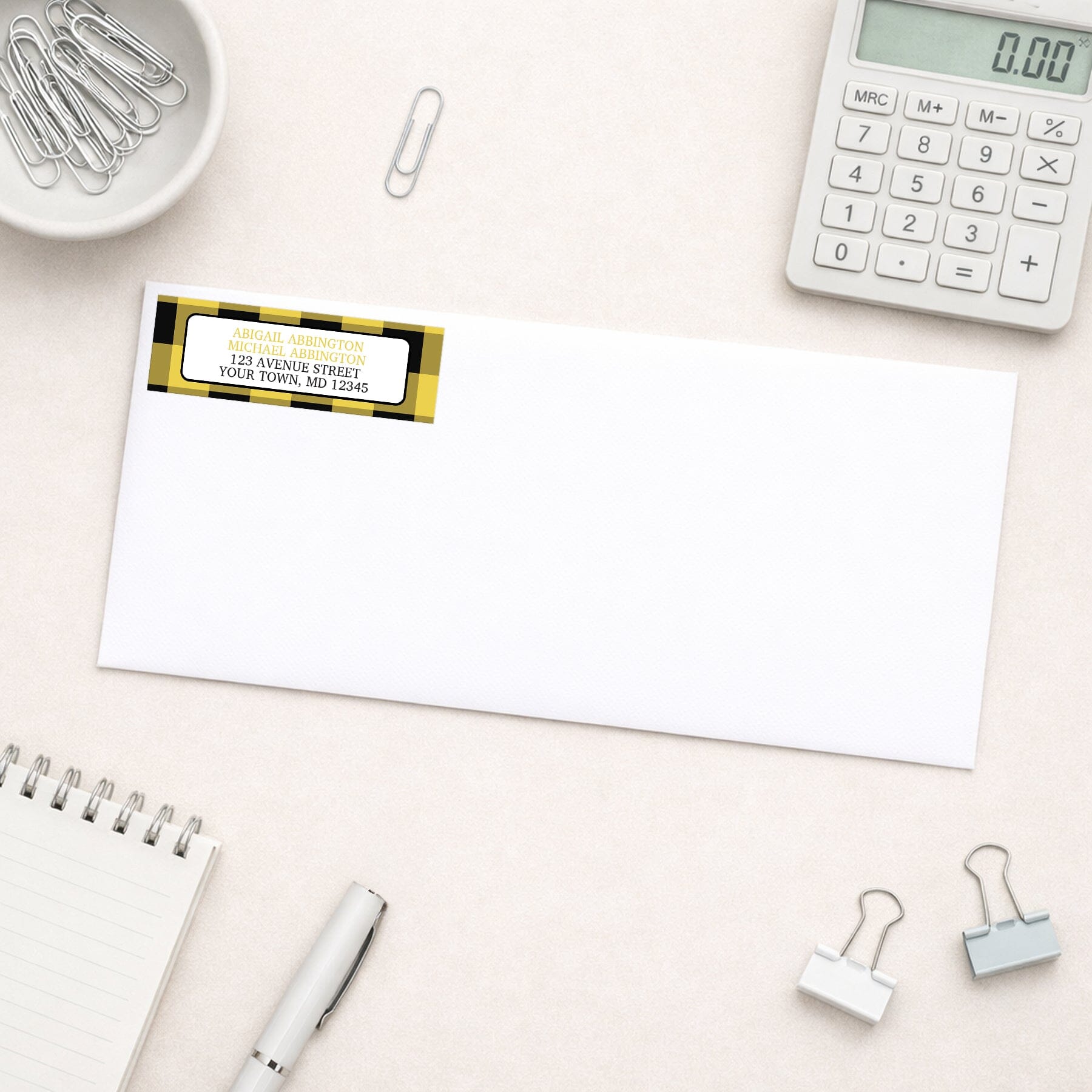 Yellow and Black Buffalo Plaid Address Label shown on a white envelope with everyday office supplies