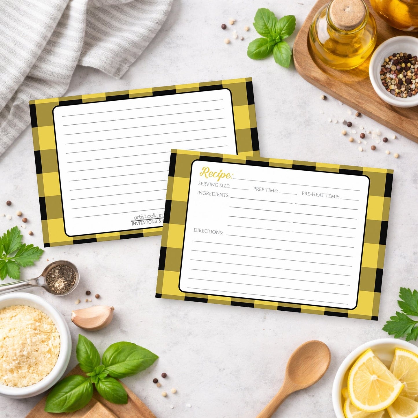 Two Yellow and Black Buffalo Plaid Recipe Cards with checkered borders on a kitchen counter with ingredients.