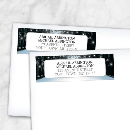 Snowy Winter Road Tree Lights Address Labels at Artistically Invited. Snowy Winter Road Tree Lights Address Labels at Artistically Invited. Snowy winter road tree lights address labels personalized with your return address. These address labels are custom printed with your return address in black and gray inside a white rectangular area outlined in gray over a background design of a snowy tree lined road filled with white holiday lights. Photo shows the labels on envelopes.