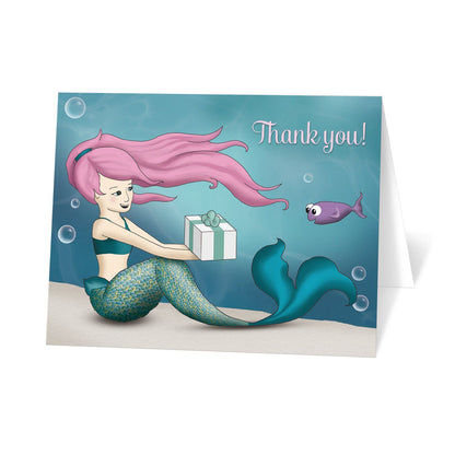 Under the Sea Mermaid Thank You Cards at Artistically Invited. Uniquely illustrated under the sea mermaid thank you cards with an under the sea theme. They are designed with a mermaid with pink hair exchanging a gift with a happy little purple fish. This underwater illustration is has an aqua blue water background. It's sprinkled with some whimsical bubbles to add some fun to the design. "Thank you!" is printed in a light pink script font in the corner over the water.