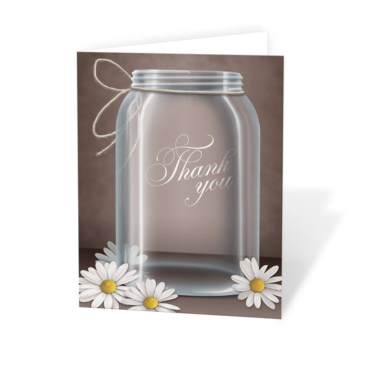 Vintage Rustic Mason Jar Daisy Thank You Cards at Artistically Invited. Stunning vintage rustic mason jar daisy thank you cards featuring a beautiful illustration of a glass mason jar with twine tied around the neck of it and white daisies laying at the bottom over a vintage brown background. "Thank you" is printed in a fancy white script font over the glass mason jar design.